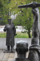 Albania, Tirane, Tirana, Statue of Stalin standing opposite another statue of figure standing with arm raised, holding a pick axe, in foreground seen from behind.
