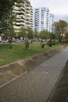 Albania, Tirane, Tirana, River Lana running past apartment blocks.