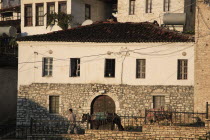 Albania, Berat, Traditional Ottoman buildings with man leading two horses.