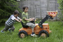 Children, Playing, Outdoor, Two twin boys playing outside on a toy tractor.