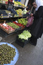 Albania, Tirane, Tirana, Female customers at fruit and vegetable stall  in the Avni Rustemi market, selecting from display including grapes, peppers and lettuce.