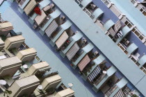 Albania, Tirane, Tirana, Angled view of balconies, striped awnings and satellite dishes on blue painted exterior facade of apartment block.