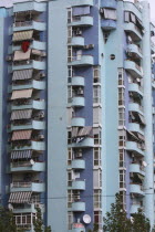 Albania, Tirane, Tirana, View of balconies and striped awnings on blue painted exterior facade of multi storey apartment block.