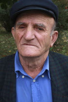 Albania, Berat, Head and shoulders portrait of an elderly man wearing cap and open-neck shirt.