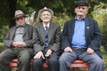 Albania, Berat, Portrait of three elderly men sitting on a park bench.
