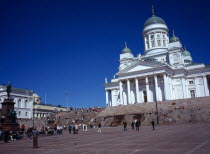 Finland, Helsinki, Senate Square and Lutheran Cathedral, White exterior facade in neo-classical style with green domed roof and statues, at top of flight of steps with crowds of visitors.