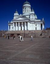 Finland, Helsinki, Senate Square and Lutheran Cathedral, White exterior facade in neo-classical style with green domed roof and statues, above flight of steps and visitors.