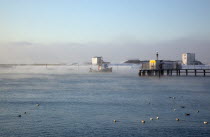 England, West Sussex, Shoreham-by-Sea, Mist rising from harbour waters on frosty morning with tug boat on the river.