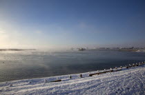 England, West Sussex, Shoreham-by-Sea, Mist rising from harbour waters on frosty morning with snow on the beach.