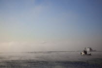England, West Sussex, Shoreham-by-Sea, Mist rising from harbour waters on frosty morning with tug boat on the river Adur.