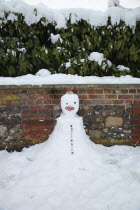 England, West Sussex, Chichester, snowman made against wall.