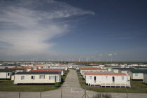 England, Kent, Romney Marsh, Old Romney, view over Camber holiday caravan park toward distant wind turbines.