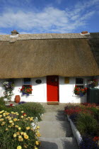 Ireland, County Waterford, Dunmore East, Small Thatched cottage with red painted door.