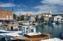 Slovenia, Koper, Port with fishing boats moored and cars parked on the quayside.