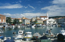 Slovenia, Koper, Port with fishing boats moored and cars parked on the quayside.