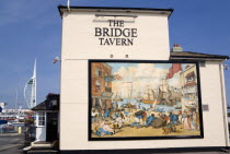 England, Hampshire, Portsmouth, The Camber in Old Portsmouth showing the Spinnaker Tower beyond the Bridge Tavern with a mural by Thomas Rowlanson of his cartoon entitled Portsmouth Point.