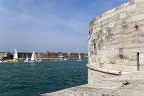 ENGLAND, Hampshire, Portsmouth, Yachts entering and leaving the harbour between The Round Tower and HMS Dolphin in Gosport on the far side of the entrance.