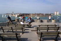 ENGLAND, Hampshire, Portsmouth, Tourists and seating on top of The Round Tower with Yachts entering and leaving the harbour between and HMS Dolphin in Gosport on the far side of the entrance.