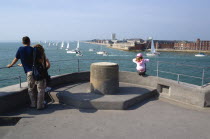ENGLAND, Hampshire, Portsmouth, Tourists family on top of The Round Tower with Yachts entering and leaving the harbour between and HMS Dolphin in Gosport on the far side of the entrance.