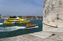 ENGLAND, Hampshire, Portsmouth, Pilot boat and catamaran Isle Of Wight passenger ferry entering the harbour between The Round Tower and HMS Dolphin in Gosport on the far side of the entrance.