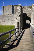 England, Hampshire, Portsmouth, Portchester Castle showing the Norman 12th Century Tower and 14th Century Keep beyond bridge over the moat built within the Roman 3rd Century Saxon Shore Fort.