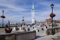 ENGLAND, Hampshire, Portsmouth, Harbour with the 170 metre tall Spinnaker Tower seen from Spice Island with people sitting in Bath Square.