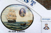 ENGLAND, Hampshire, Portsmouth, Wall paintings outside a tattooist's parlour underneath railway arches at Portsmouth Harbour Station showing a sailor with the local football club slogan Play Up Pompey...