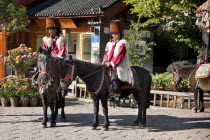 China, Yunnan Province, Lijiang, Naxi men on horseback wearing traditional costume including Red panda skin hats.