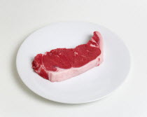 Food, Red Meat, Beef, Slice of raw uncooked sirloin steak on a round white plate against a white background.