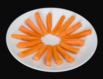 Food, Vegetables, Carrots, Slices of raw uncooked carrot on a white plate against a black background.