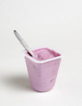 Food, Organic, Yogurt, Yeo Valley probiotic blueberry fruit yogurt with spoon in pot against a white background.