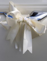 Religion, Christian, Weddings, Cream ribbon tied in bow on door handle of vintage white Daimler wedding car.