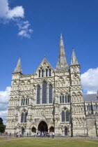 England, Wiltshire, Salisbury, People on the grass of the Close in front of the West Front main entrance of the 13th Century Early English Gothic Cathedral Church of the Blessed Virgin Mary with the t...