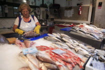 Portugal, Lisbon, A vendor descales a fish at her stall in the Ribeira market.