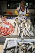 Portugal, Lisbon, A vendor descales a fish at her stall in the Ribeira market.