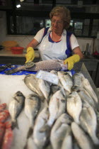 Portugal, Lisbon, A vendor descales a fish at her stall in the Ribeira market.