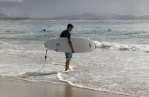 Australia, New South Wales, Byron Bay, young surfer walking toward the sea.