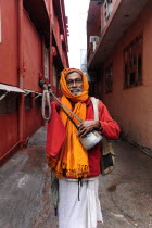 India, Uttarakhand, Hardiwar, Portrait of Saddhu standing in narrow street during Kumbh Mela, biggest religious festival where many different traditions of Hinduism come together to bathe in the Gange...
