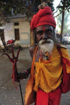 India, Uttarakhand, Hardiwar, Portrait of a Saddhu carrying a trident or trishul ritual staff associated with the god Shiva during Kumbh Mela, Indias biggest religious festival where many different tr...