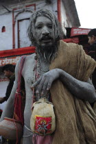 India, Uttarakhand, Hardiwar, Saddhu with body covered with ash and carrying skull painted with depiction of Shiva during Kumbh Mela, Indias biggest religious festival where many different traditions...