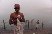 India, Uttarakhand, Hardiwar, Pilgrims beside the River Ganges emerge from the mist during Kumbh Mela, Indias biggest religious festival where many different traditions of Hinduism come together to ba...