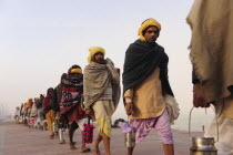 India, Uttarakhand, Hardiwar, Line of pilgrims carrying tiffin boxes during Kumbh Mela, Indias biggest religious festival where many different traditions of Hinduism come together to bathe in the holy...