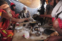 India, Uttarakhand, Hardiwar, Saddhus preparing meal over open fire inside tent during Kumbh Mela, Indias biggest religious festival.