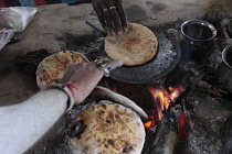 India, Uttarakhand, Hardiwar, Saddhu Baba Gajender Girri Marraj with his body covered in ash, cooking parathas on hot plate over open fire.