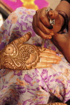 India, Uttarakhand, Hardiwar, Cropped shot of woman applying henna paste in decorative pattern to the palm of the hand of another.