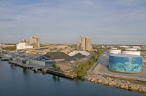 USA, Florida, Tampa, An attempt to put an environment friendly face on oil storage tanks along Maritime Boulevard, heaps of coal and chemicals in front of industrial plant.