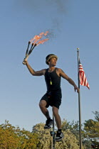 USA, Florida, Key West, Mallory Square, Fire Juggler on a giraffe unicycle prepares to juggle flaming torches during a performance for tourists.