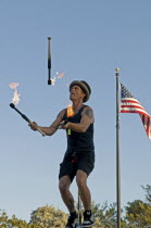 USA, Florida, Key West, Mallory Square, Fire Juggler on a giraffe unicycle prepares to juggle flaming torches during a performance for tourists.