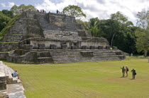 Belize, Altun Ha,Tourists in front and on top of the Temple of Masonry Altars in Plaza B of the Mayan ruins, A large carved jade head of the Mayan sun god Kinich Ahau was found in the temple.