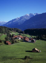 Switzerland, Bern, Brunigen, Small hamlet of Brunigen near town of Meiringen. Cluster of buildings in green valley surrounded by trees with mountain backdrop.